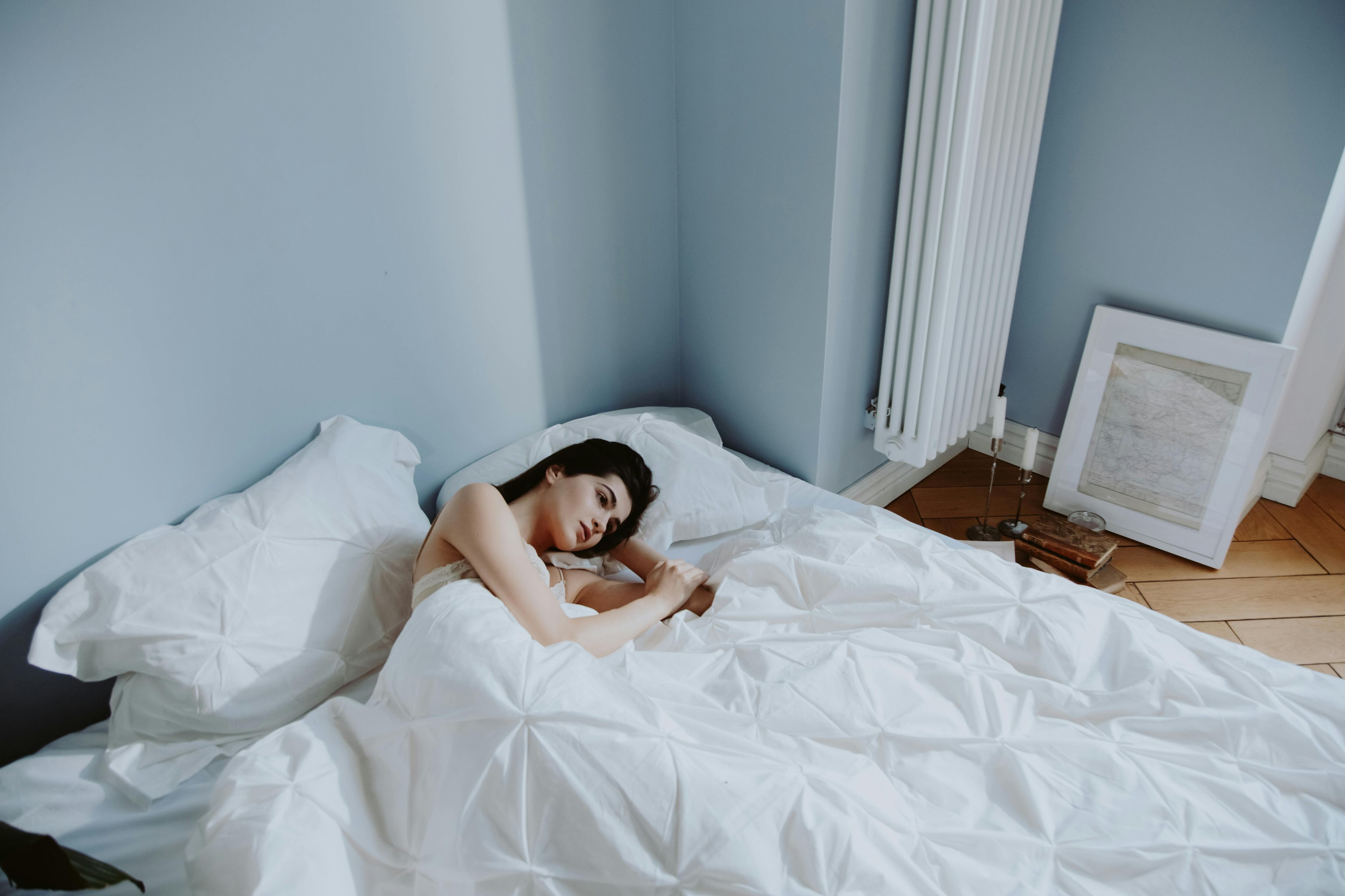 Mulher na cama deitada de olho aberto